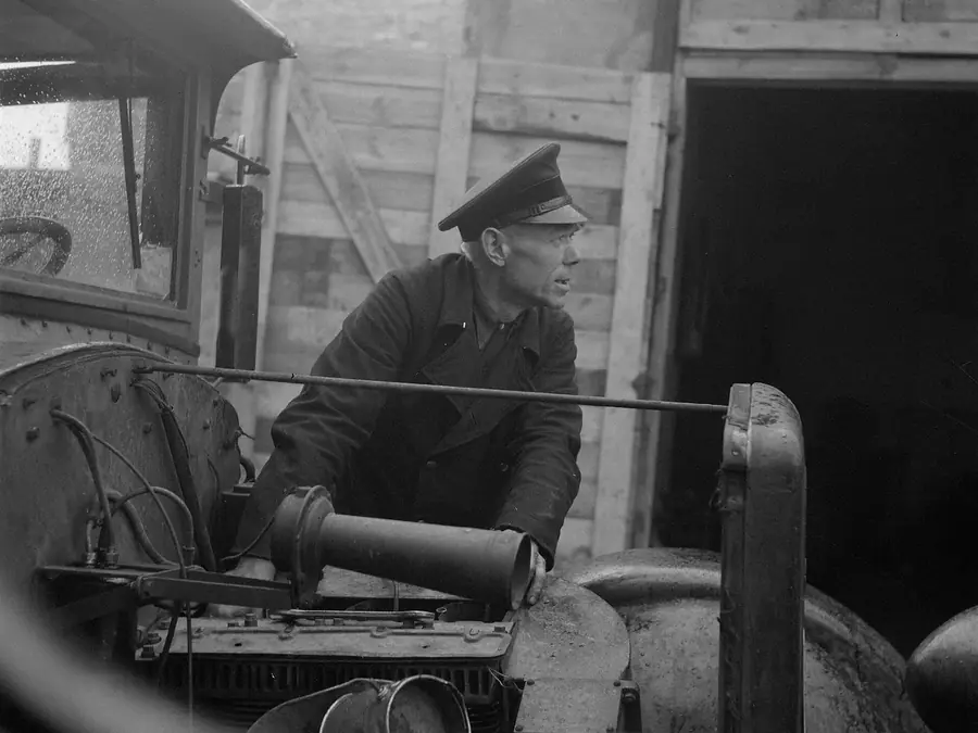 Archive photograph of a driver in a peaked cap and dark coat at the controls